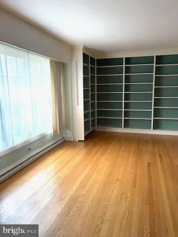 a view of an empty room with a window and wooden floor