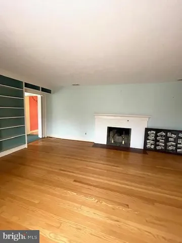 a view of empty room with wooden floor and fireplace