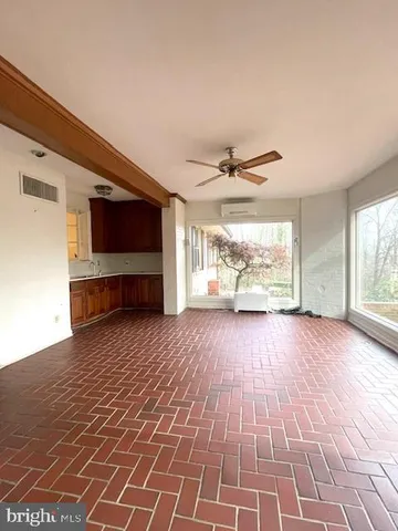a view of a livingroom with wooden floor a ceiling fan and windows