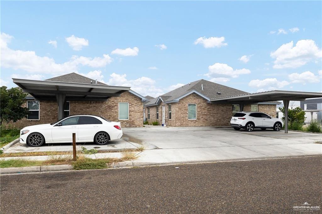 Single story home featuring brick siding and covered and uncovered parking
