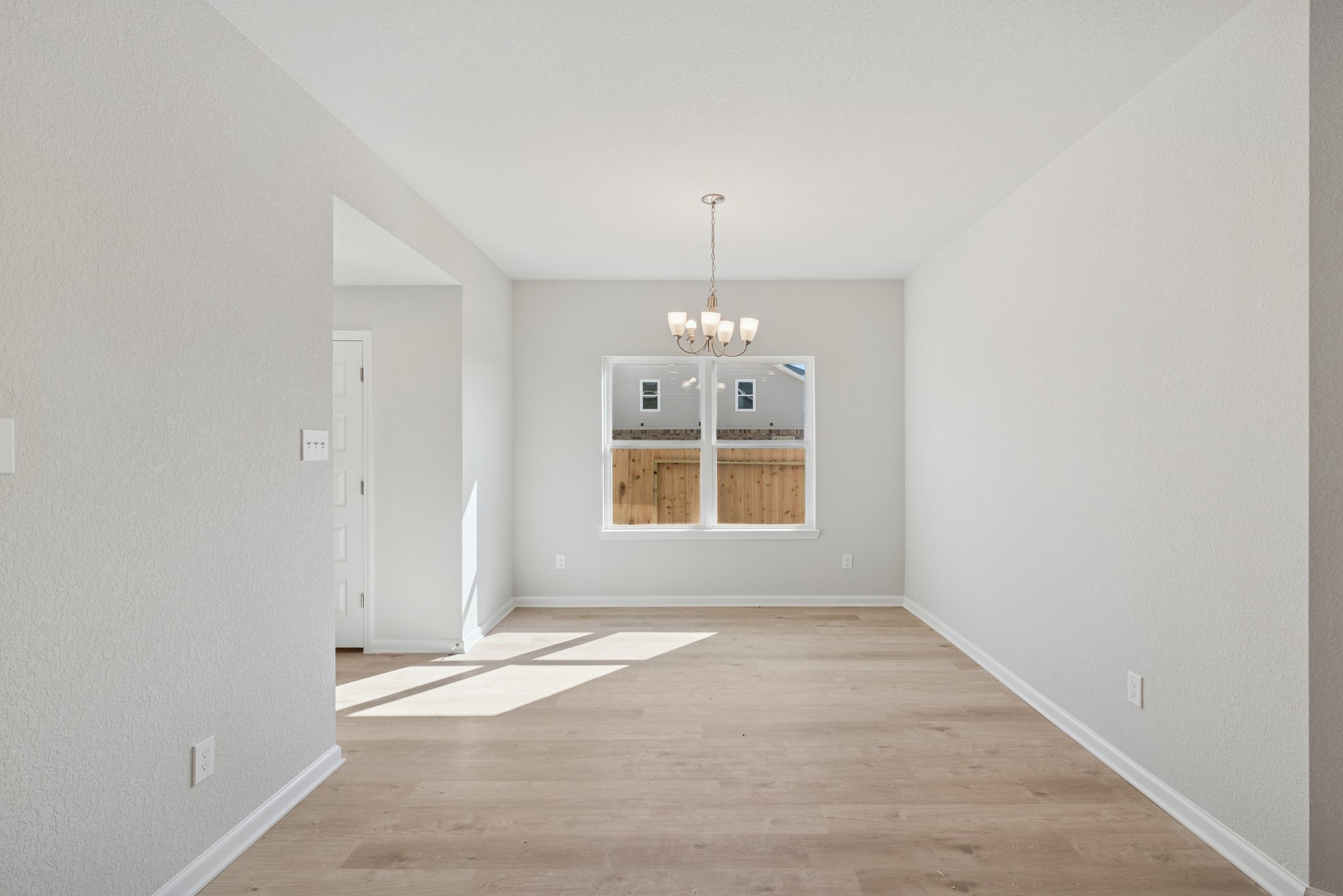 9761 Enclave Ridge Road Willis, TX 77318 - Photo 5 of 28 an empty room with chandelier and windows