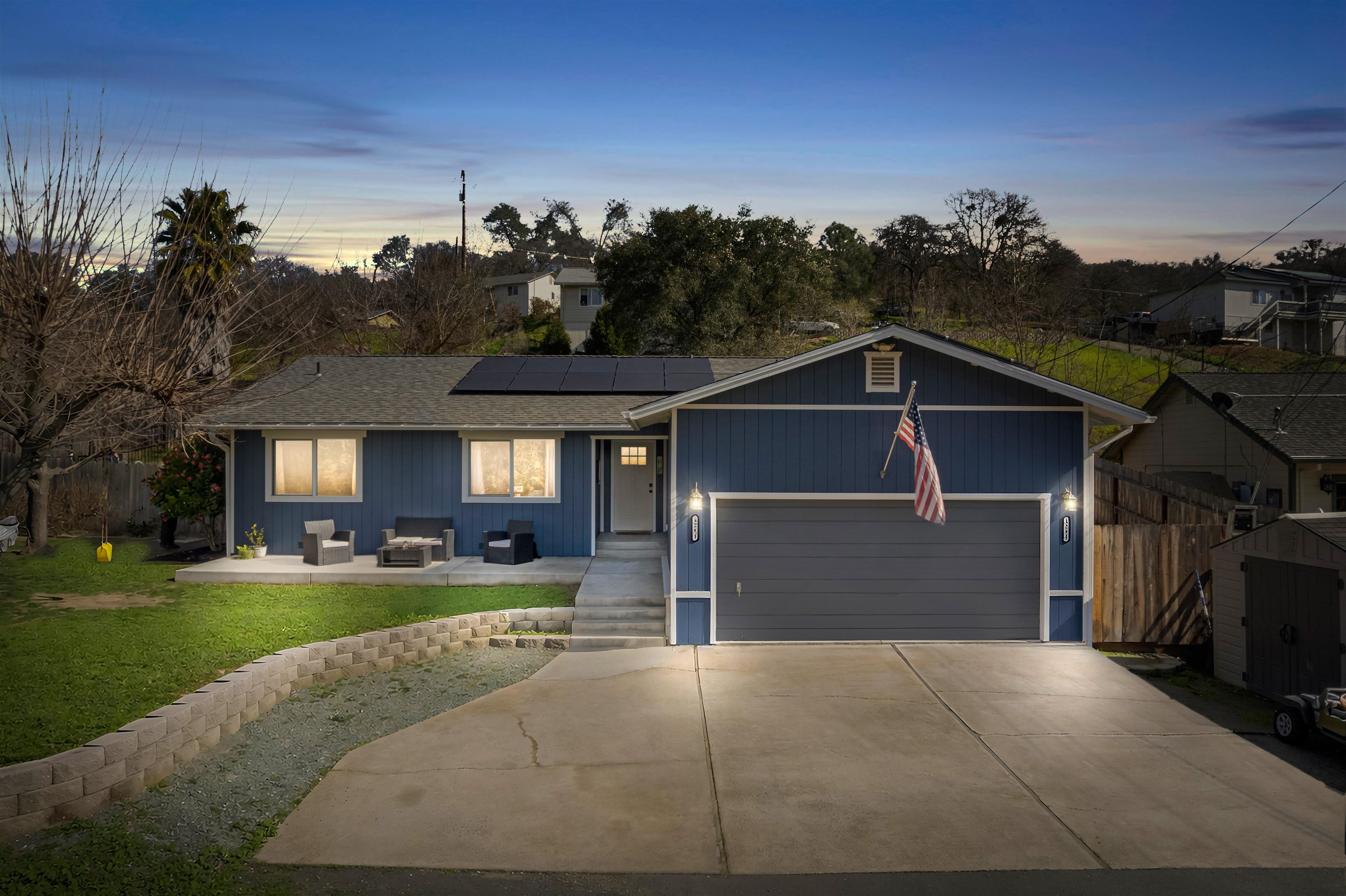View of front of house with roof mounted solar panels, concrete driveway, an attached garage, outdoor lounge area, and a patio area
