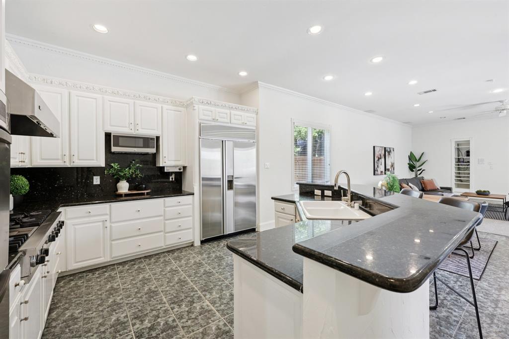 6065 Dilbeck Lane Dallas, TX 75240 - Photo 8 of 40 a kitchen with stainless steel appliances granite countertop a sink dishwasher a refrigerator a microwave oven with white cabinets and wooden floor