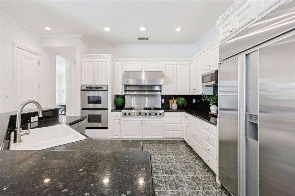 6065 Dilbeck Lane Dallas, TX 75240 - Photo 9 of 40 a kitchen with stainless steel appliances kitchen island granite countertop a refrigerator and a stove top oven