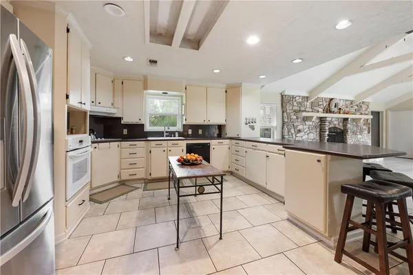 a kitchen with stainless steel appliances granite countertop a refrigerator and a stove top oven