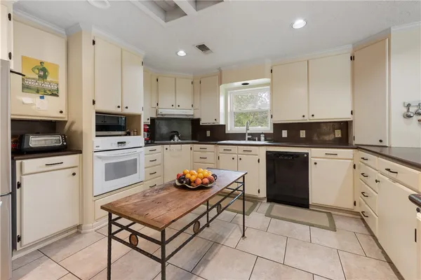 a kitchen with stainless steel appliances kitchen island granite countertop a sink a stove top oven a counter space and cabinets
