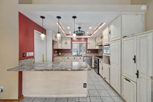 a large kitchen with stainless steel appliances kitchen island granite countertop a refrigerator a stove a sink and white cabinets