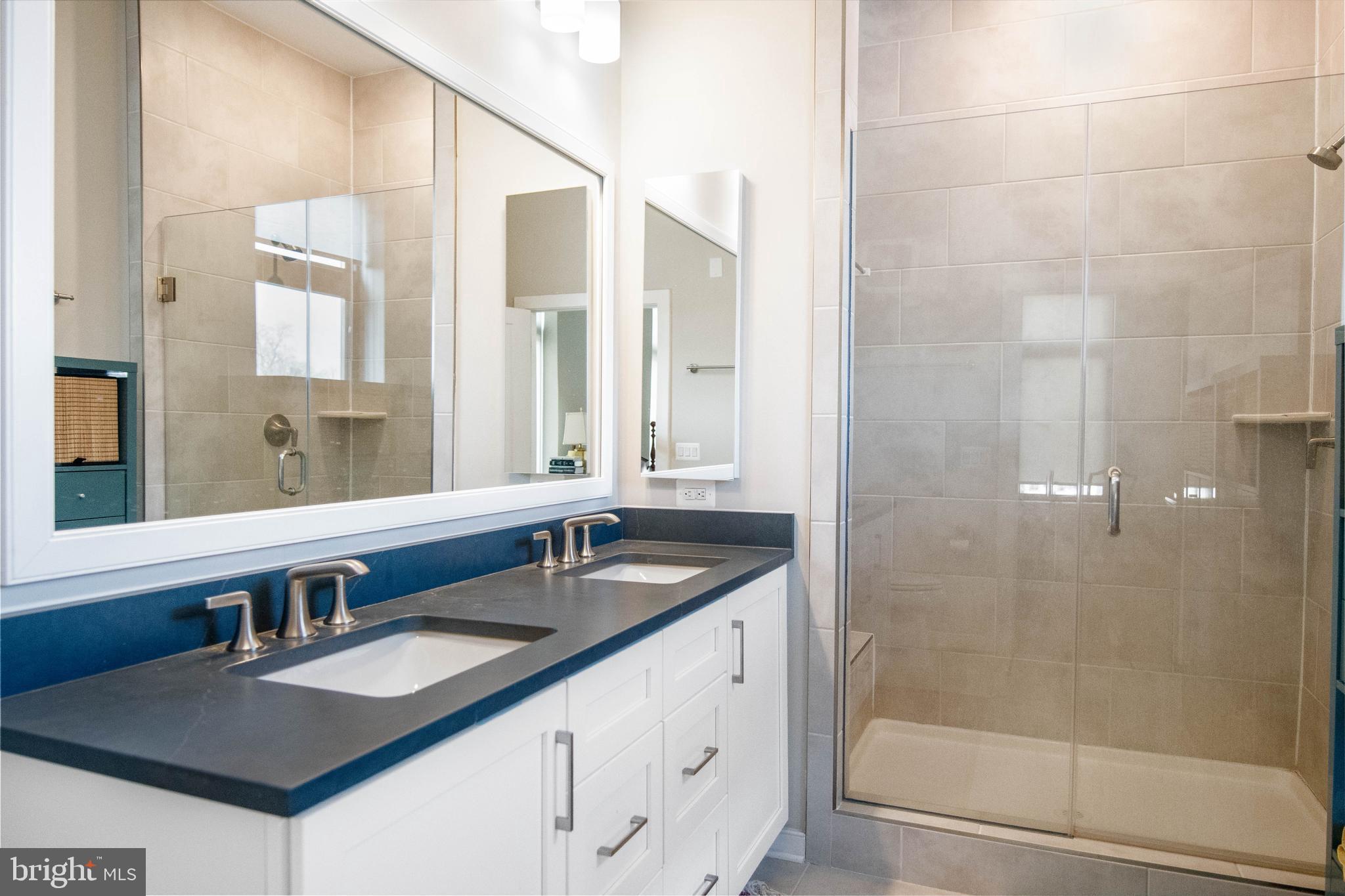 2 Stationmaster Street Southeast, Unit 302 Leesburg, VA 20175 - Photo 32 of 57 a bathroom with a granite countertop sink a mirror a window and a shower