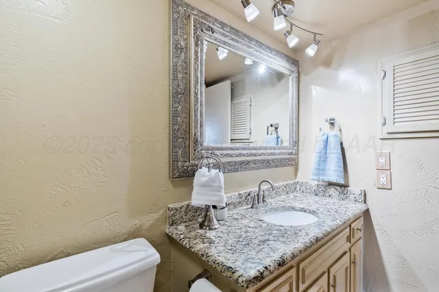 a bathroom with a granite countertop sink a toilet and a mirror