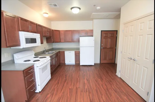 a kitchen with a refrigerator a stove top oven a sink and cabinets with wooden floor