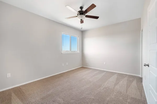 an empty room with chandelier fan and windows