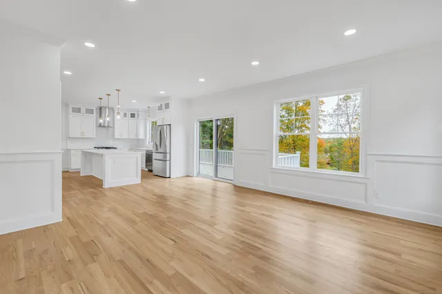 a view of an empty room with window and wooden floor