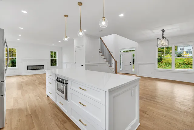 a kitchen with a stove a sink a wooden floor and a large window