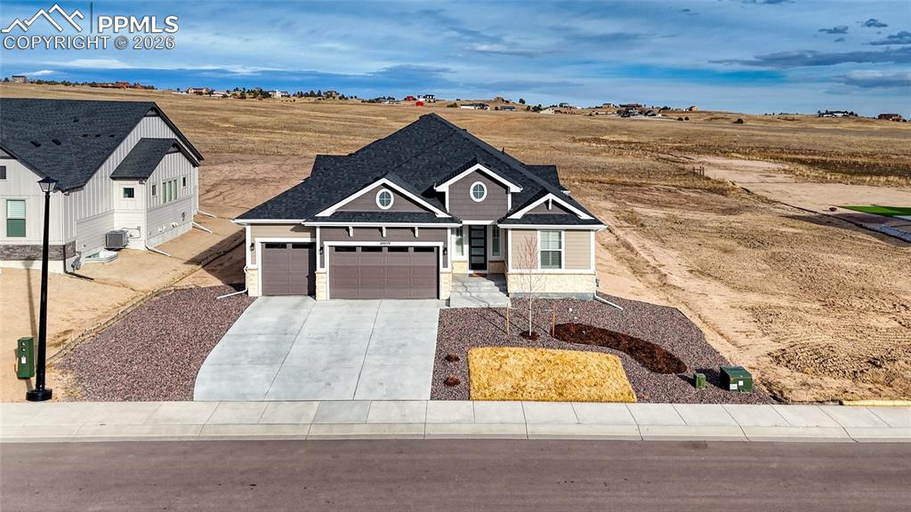 View of front of home with an attached garage, concrete driveway, and stone siding