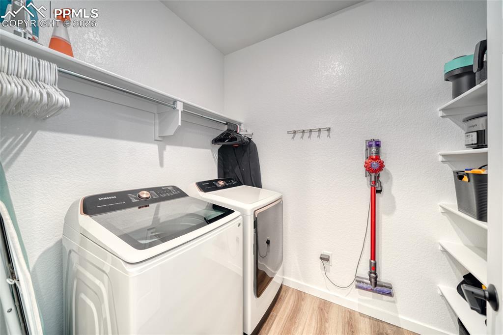 10059 Owl Perch Loop Colorado Springs, CO 80908 - Photo 29 of 50 Laundry room featuring a textured wall, light wood-style floors, and washer and clothes dryer