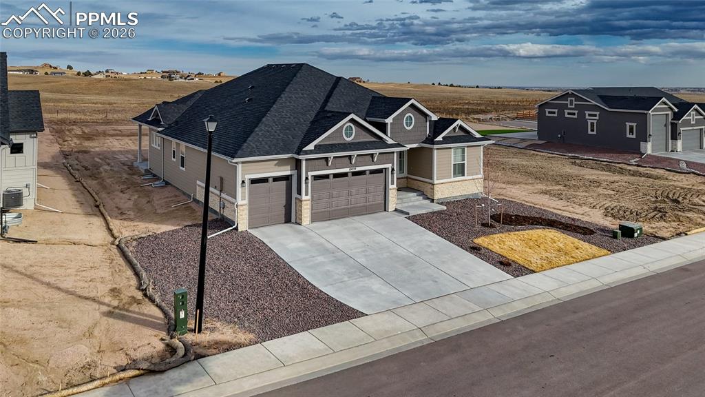 10059 Owl Perch Loop Colorado Springs, CO 80908 - Photo 3 of 50 View of front of property featuring a garage, concrete driveway, stone siding, and roof with shingles