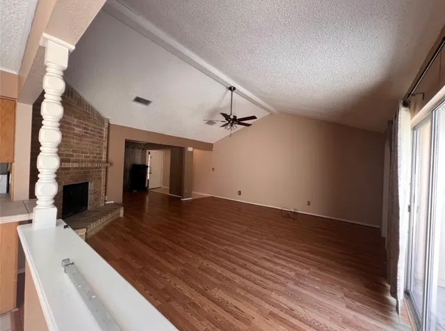 an empty room with wooden floor fireplace and windows
