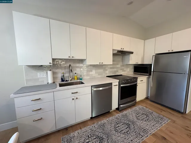 a kitchen with granite countertop a refrigerator stove top oven and cabinets