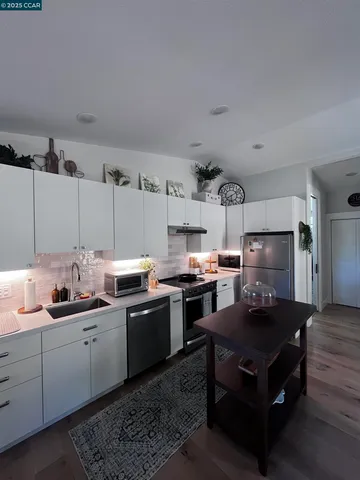 a kitchen with kitchen island granite countertop a sink dishwasher stove and cabinets