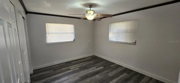 a room with chandelier fan and windows