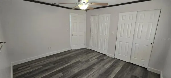 a view of an empty room with chandelier fan and closet area
