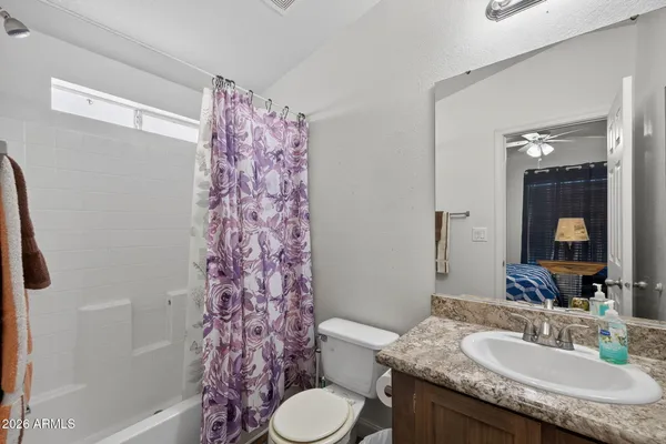 a bathroom with a granite countertop sink toilet a mirror and shower curtain