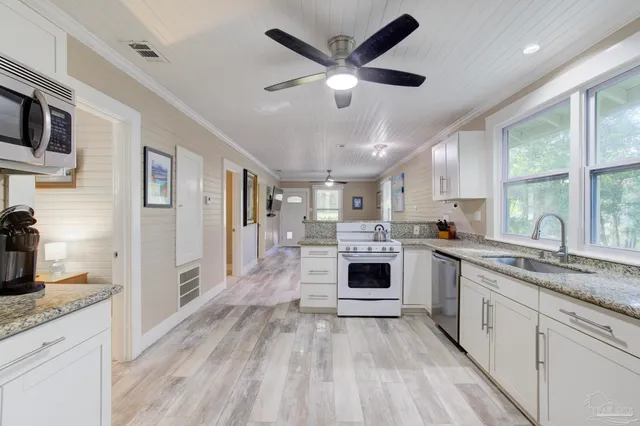 a large white kitchen with cabinets a sink and appliances