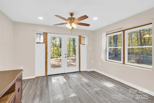 a view of an empty room with a window and wooden floor