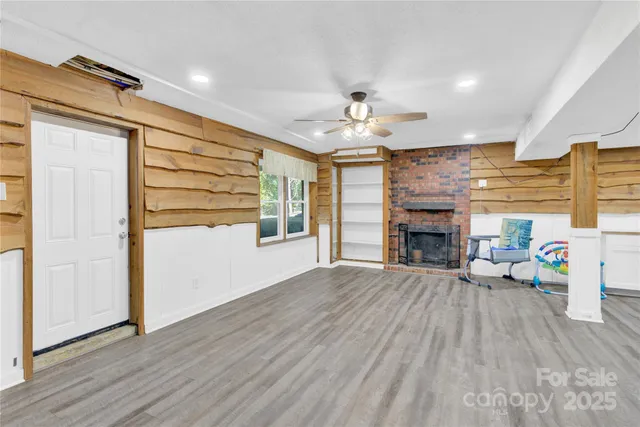 an empty room with wooden floor fireplace and windows