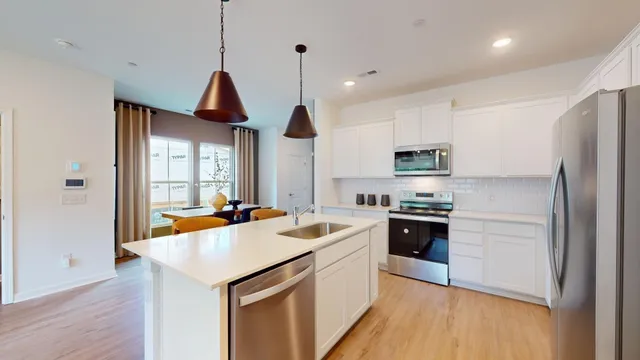 a kitchen with stainless steel appliances a stove a sink a microwave a refrigerator a stove a dining table and chairs