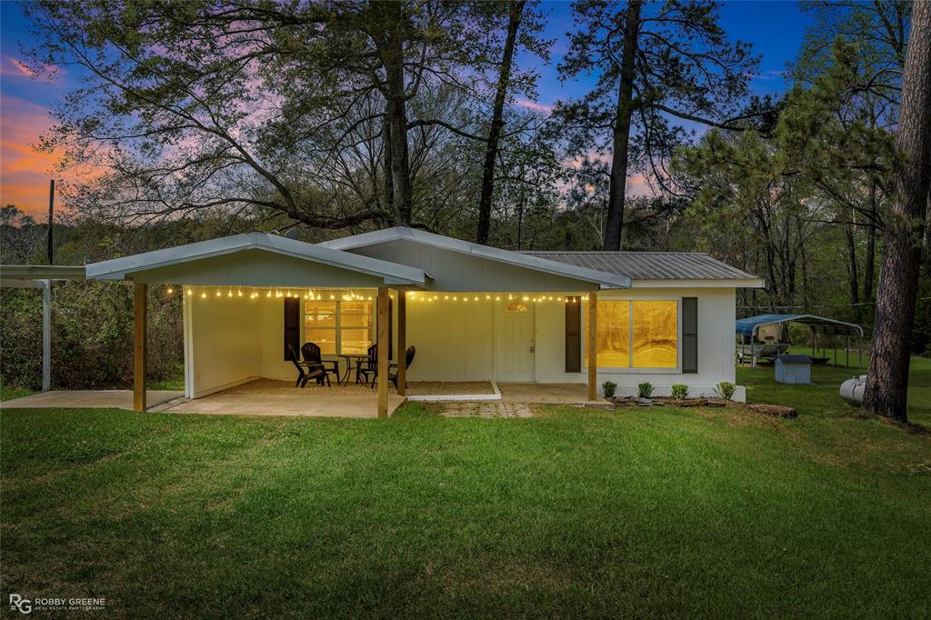 Rear view of house featuring a lawn, a patio area, a metal roof, and a carport