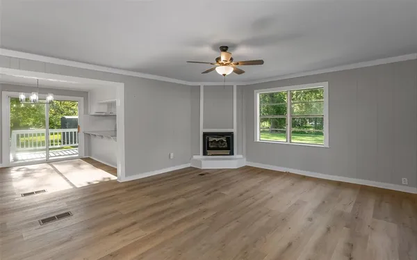a view of an empty room with a window and wooden floor