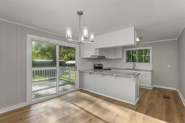 a kitchen with stainless steel appliances granite countertop a stove a sink dishwasher a refrigerator white cabinets and wooden floor