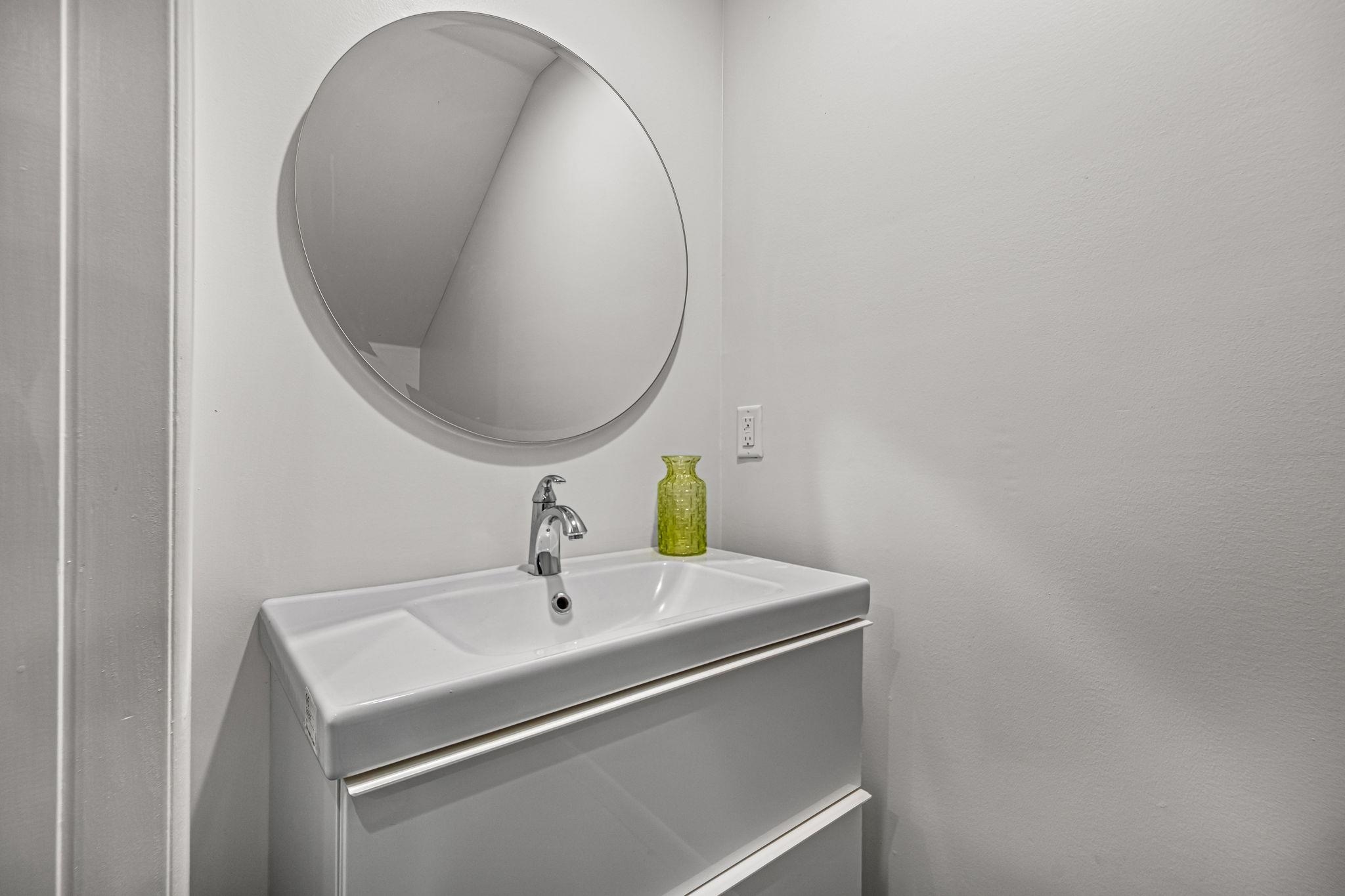448 Tennessee Street Memphis, TN 38103 - Photo 27 of 39 Modern vanity with an integrated basin sink, chrome faucet, and a large circular mirror