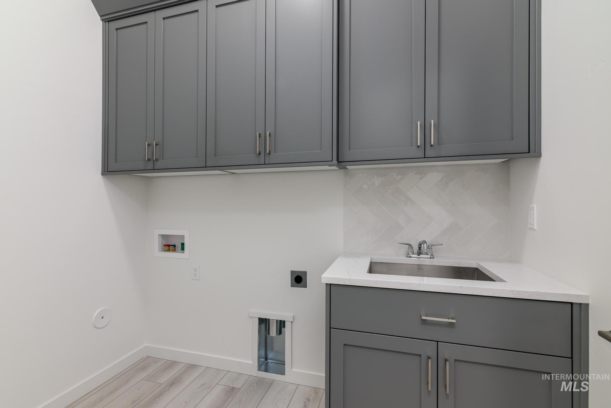 5416 Sparky Avenue Caldwell, ID 83607 - Photo 26 of 42 Laundry area with washer hookup, electric dryer hookup, light wood-style floors, and cabinet space