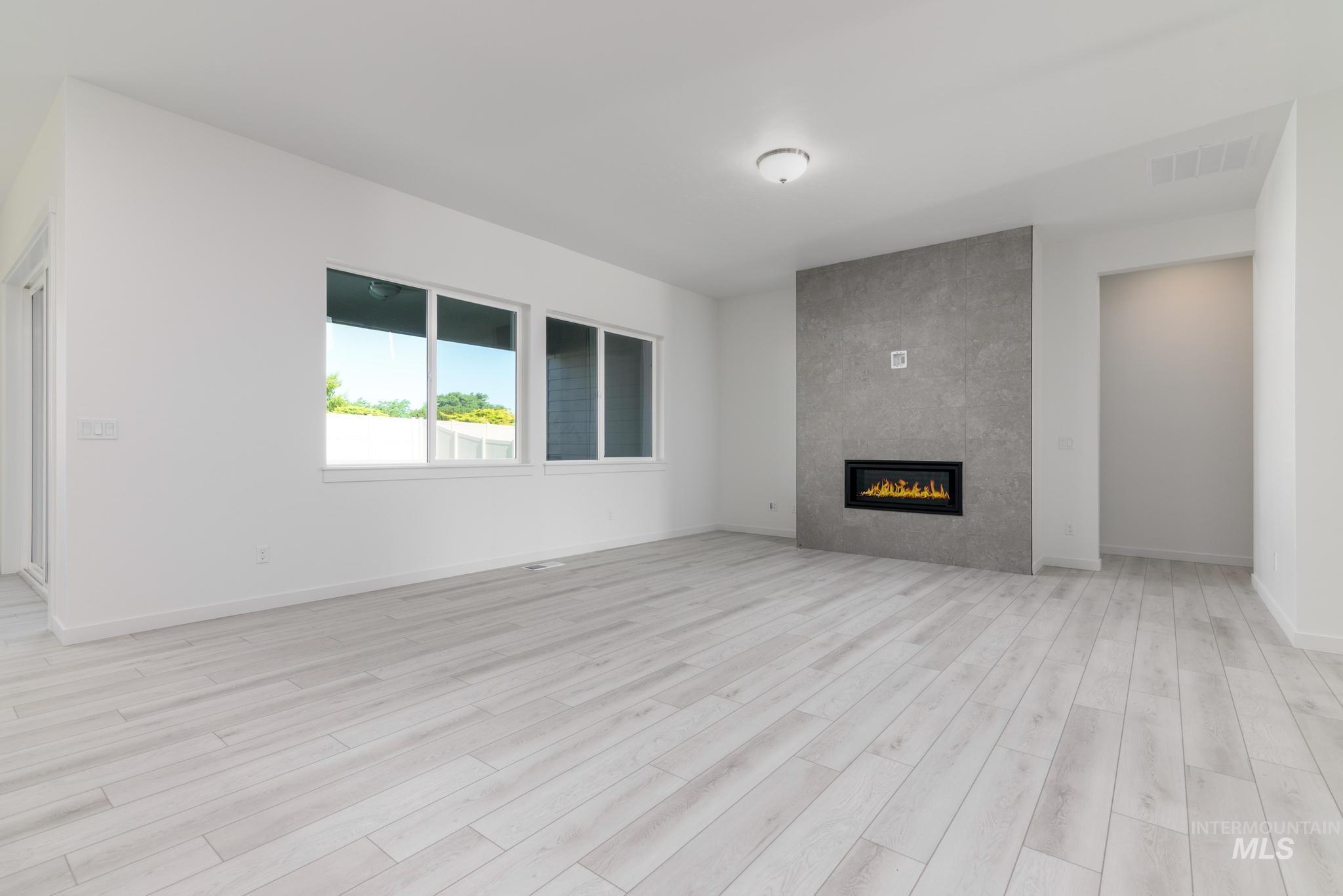 5416 Sparky Avenue Caldwell, ID 83607 - Photo 5 of 42 Unfurnished living room with a tiled fireplace and light wood-style flooring