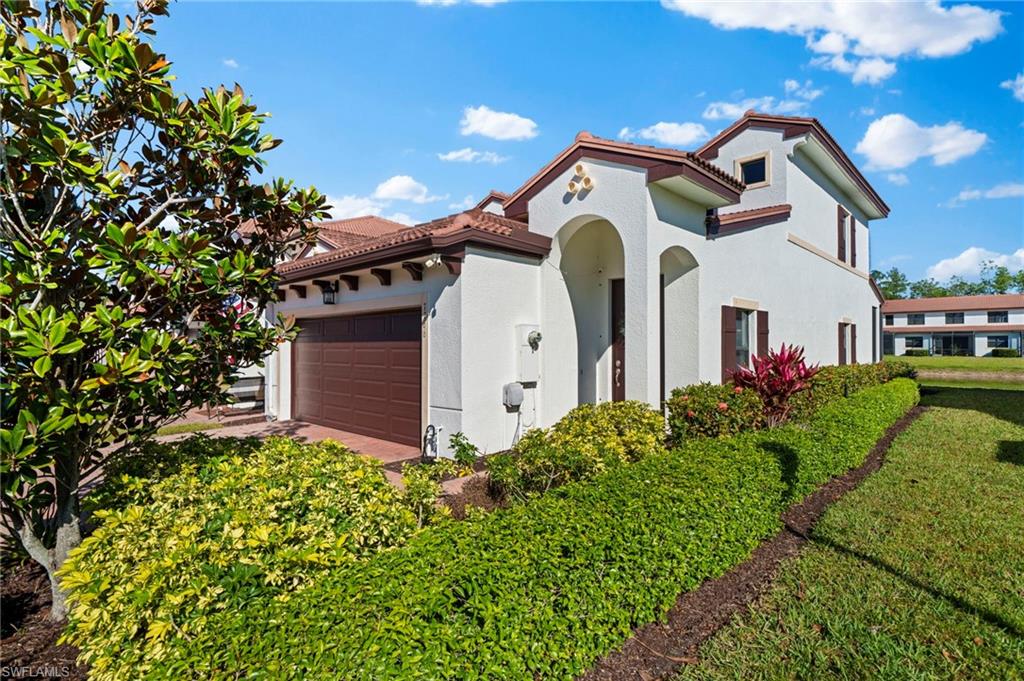View of front of property with a tiled roof, an attached garage, and stucco siding