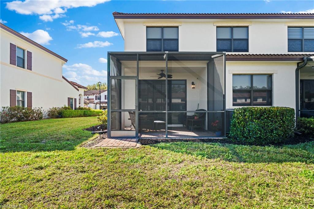 7766 Bristol Circle Naples, FL 34120 - Photo 23 of 30 Back of property with ceiling fan, a sunroom, a lawn, and stucco siding