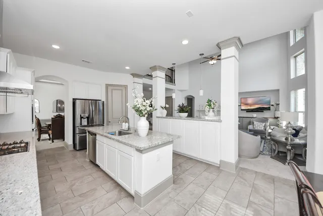 a large white kitchen with a refrigerator a stove a sink and a dining table with wooden floor