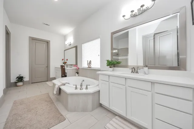 a bathroom with a tub a double vanity sink and mirror