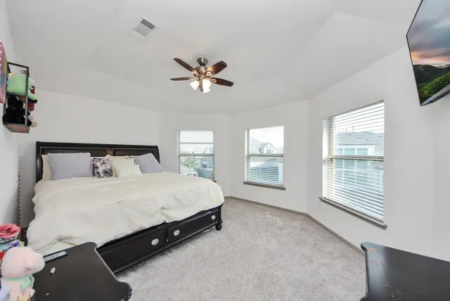 a spacious bedroom with a bed a flat screen tv and a large window with the outer view