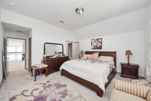 a bedroom with a bed and a lamp on dresser