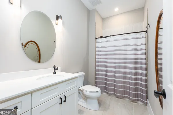 a bathroom with a sink a toilet a mirror and shower