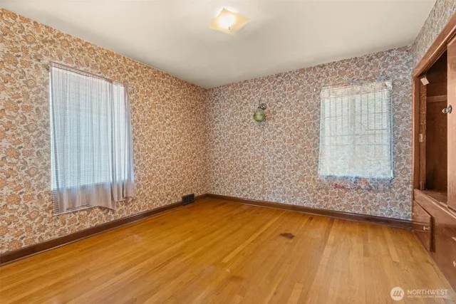 a view of an empty room with a window and wooden floor