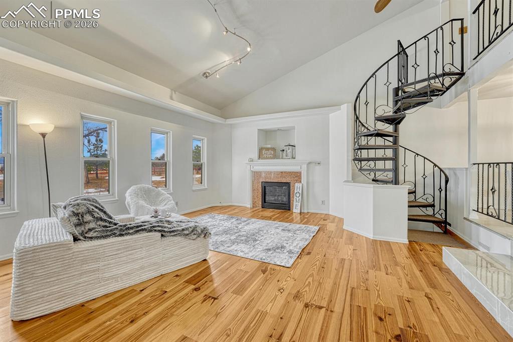 7815 Maverick Road Colorado Springs, CO 80908 - Photo 8 of 41 Cozy living room with vaulted ceilings and natural wood floors. View of custom spiral staircase to loft.