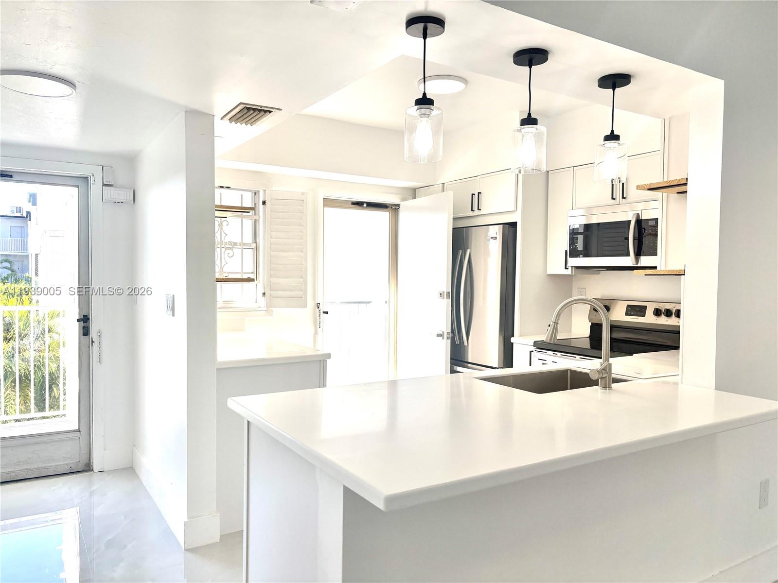 9159 Southwest 77th Avenue, Unit 314 Miami, FL 33156 - Photo 13 of 53 a kitchen with stainless steel appliances kitchen island granite countertop a sink and refrigerator