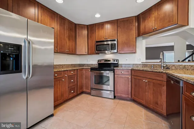 a kitchen with stainless steel appliances granite countertop a stove a sink dishwasher a refrigerator and a microwave oven