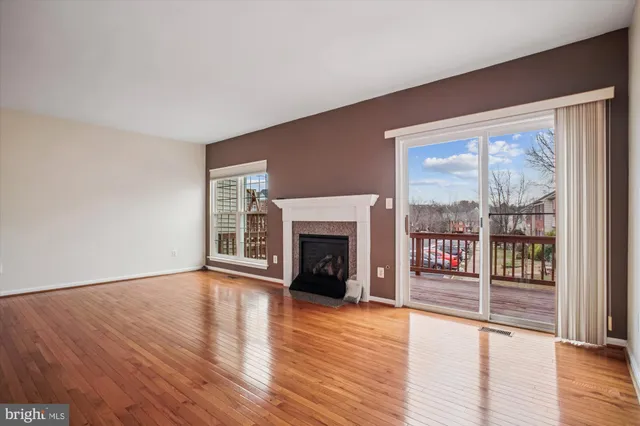 a view of an empty room with wooden floor fireplace and a window