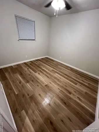 a view of a room with a ceiling fan and wooden floor
