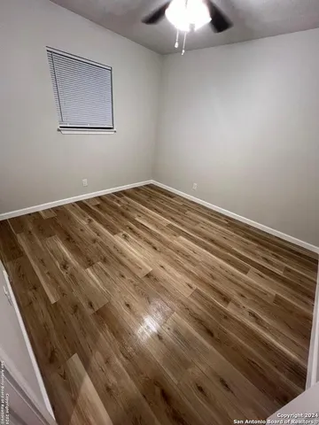 a view of a room with a ceiling fan and wooden floor